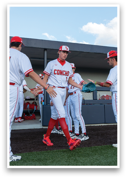 A group of baseball players wearing red and white uniforms. Description generated by AI