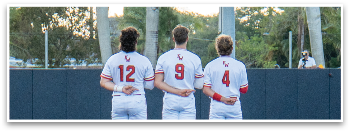 Three baseball players standing on a field. Description generated by AI