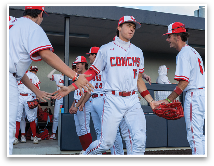 A group of baseball players wearing red and white uniforms. Description generated by AI
