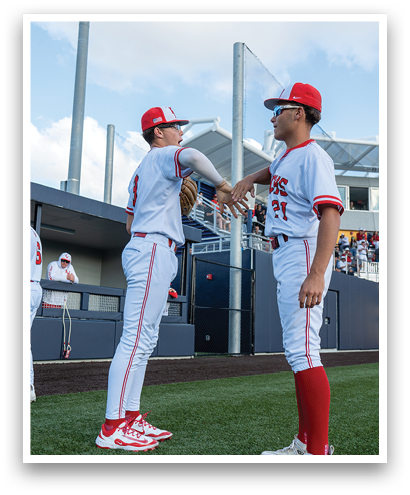 Two baseball players wearing red and white uniforms shake hands. Description generated by AI