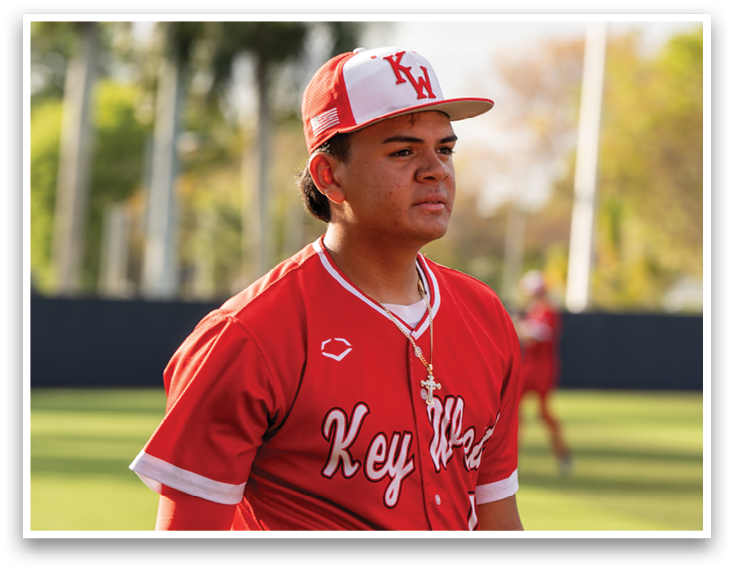 A baseball player wearing a red jersey with the word Key West on it. Description generated by AI