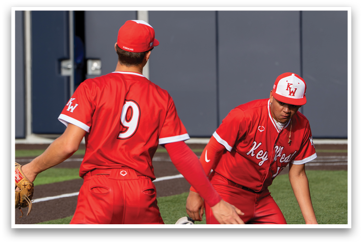 Two baseball players wearing red uniforms. Description generated by AI