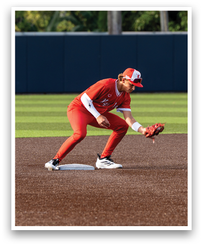 A baseball player in a red uniform is kneeling on the field. Description generated by AI