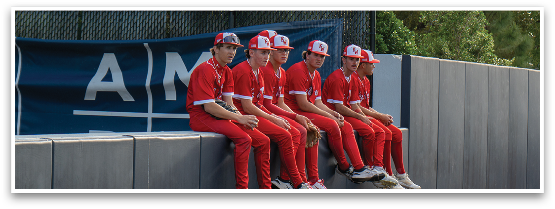 A group of young men wearing red shirts and red pants are sitting on a wall. Description generated by AI