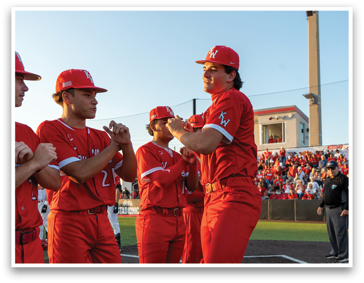 A group of baseball players wearing red and white uniforms. Description generated by AI