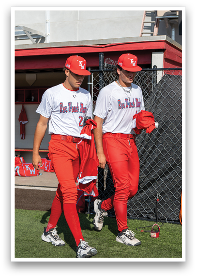 Two baseball players wearing red and white uniforms. Description generated by AI
