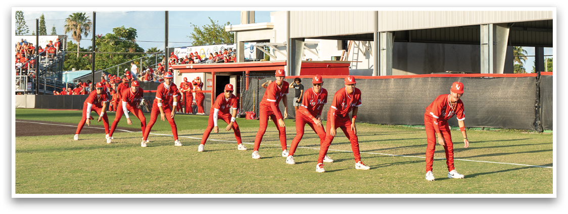 A group of people in red and white uniforms are standing on a field. Description generated by AI