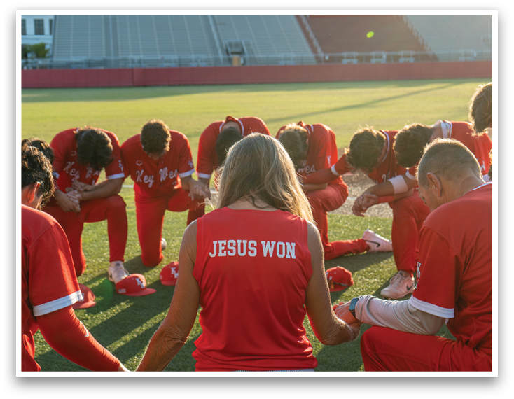 A group of people wearing red shirts and kneeling down. Description generated by AI