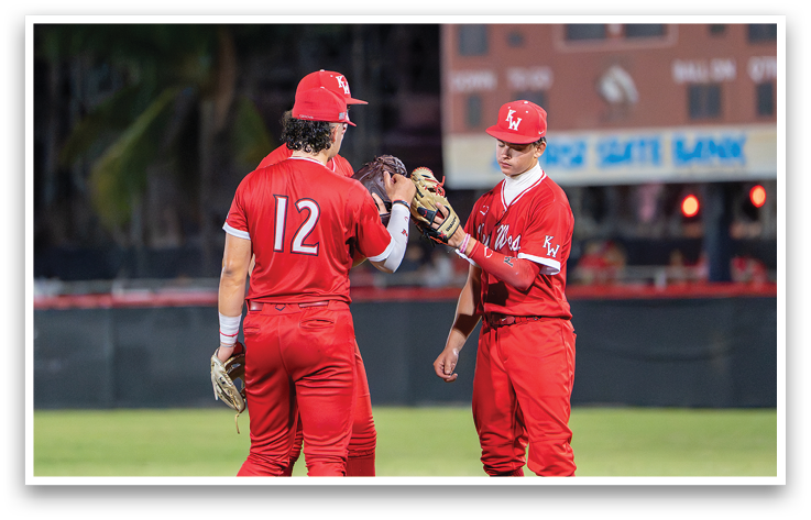 Two baseball players wearing red uniforms shake hands. Description generated by AI