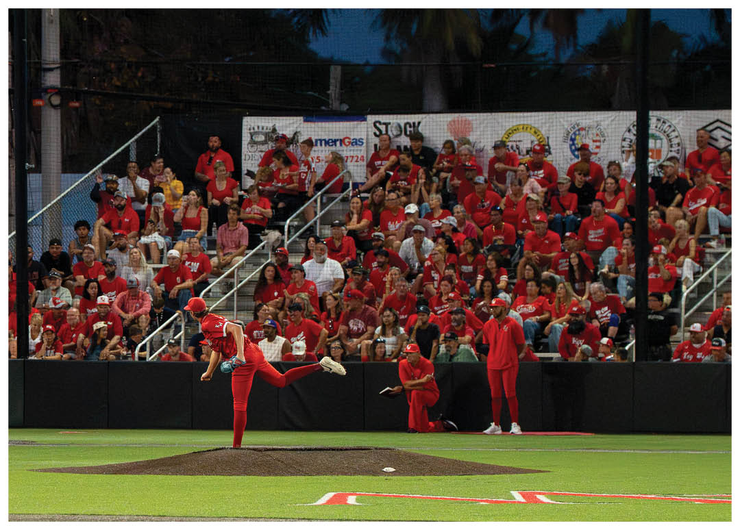 A baseball player in a red shirt and white pants is pitching a ball. Description generated by AI