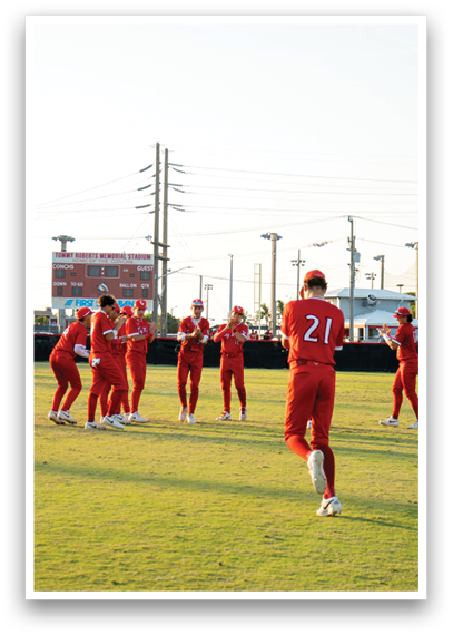 A group of people wearing red and white uniforms are standing on a grassy field. Description generated by AI