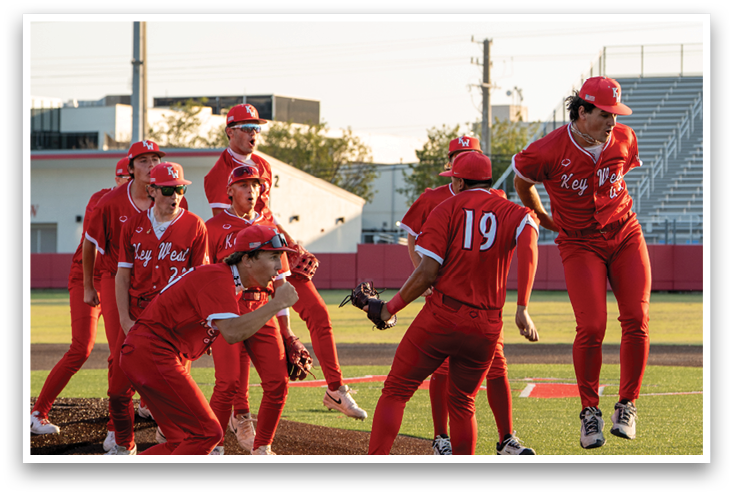 A group of people wearing red and white uniforms are celebrating on a field. Description generated by AI