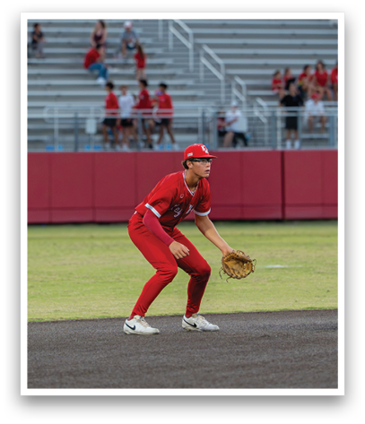 A baseball player in a red uniform is crouching on the field. Description generated by AI