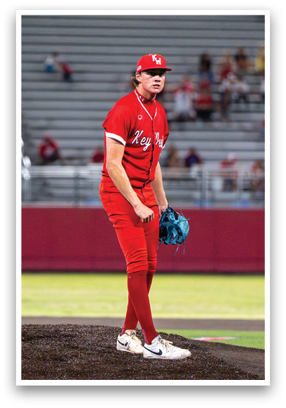 A baseball player in a red uniform stands on the pitcher's mound. Description generated by AI