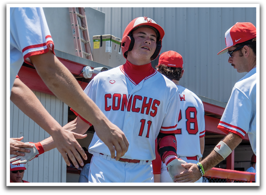 A group of baseball players wearing red and white uniforms. Description generated by AI