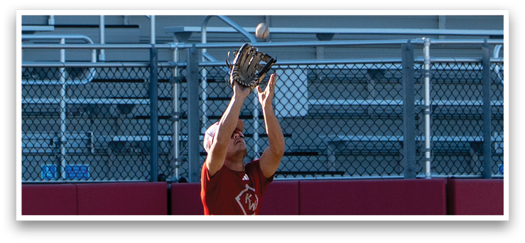 A baseball player in a red shirt and grey pants catching a ball. AI generated content