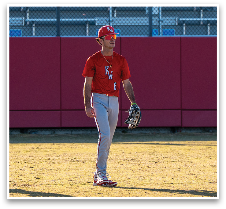 A baseball player wearing a red shirt and white pants stands on a field. AI generated content