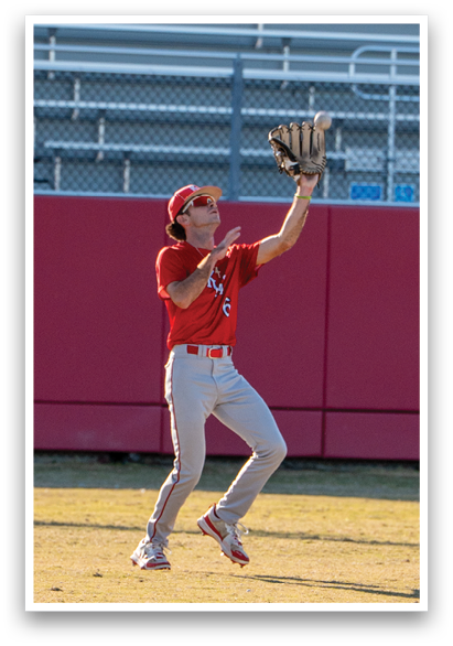 A baseball player wearing a red shirt and white pants is leaping in the air to catch a ball. AI generated content