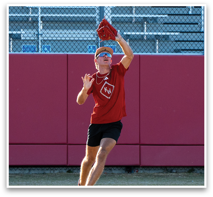 A man wearing a red shirt and sunglasses is jumping in the air to catch a baseball. AI generated content