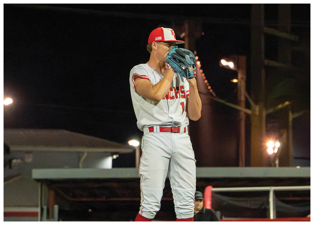 A baseball player in a white uniform stands on a mound, holding a baseball glove. AI generated content