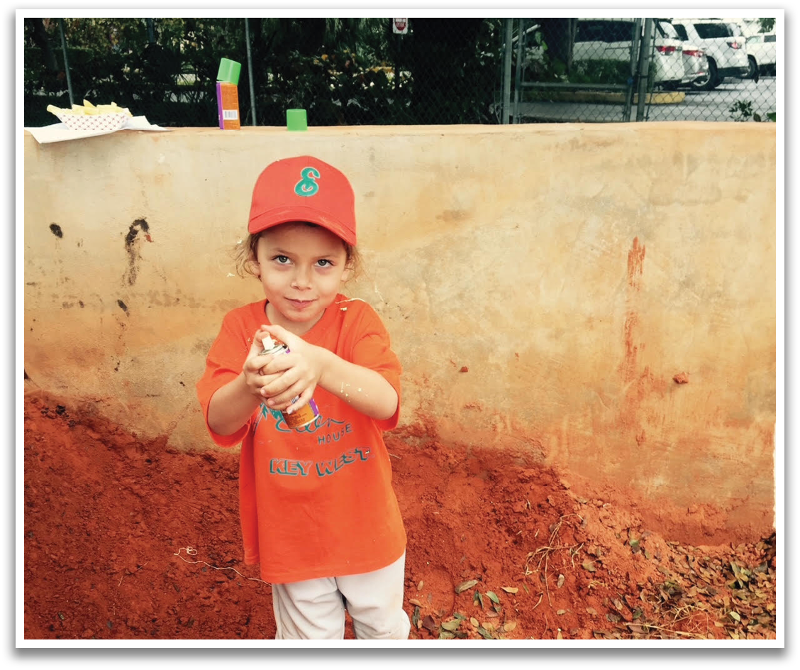 A young boy wearing an orange shirt and a baseball cap is holding a baseball in his hand. AI generated content