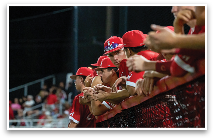 A group of people wearing red hats and shirts are standing on a baseball field. AI generated content