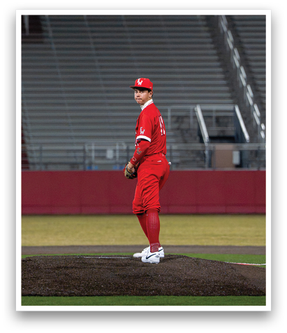 A man in a red shirt and red pants is standing on a pitcher's mound, holding a baseball. AI generated content