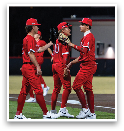 Three baseball players in red uniforms are standing on a field, talking to each other. One of the players is holding a baseball glove. AI generated content