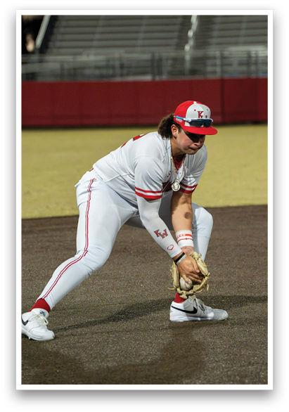 A baseball player in a white uniform is kneeling on the ground, holding a baseball glove, and looking down at the ground. AI generated content