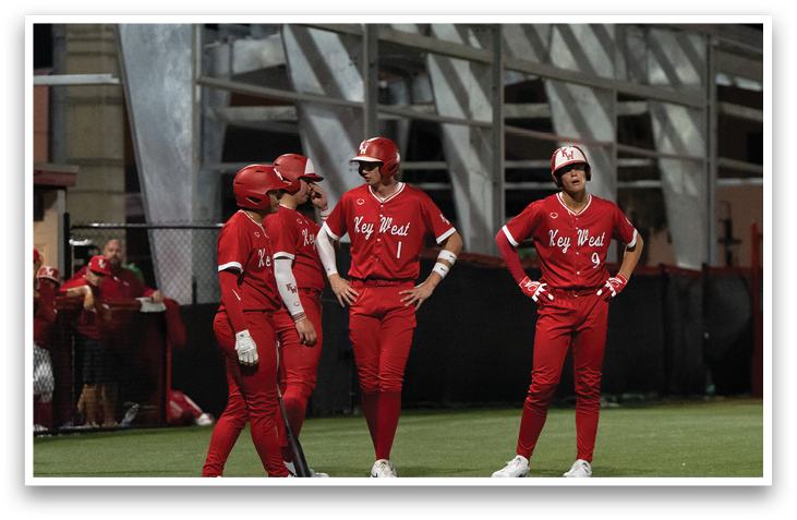 Three baseball players wearing red uniforms are standing on a field. AI generated content