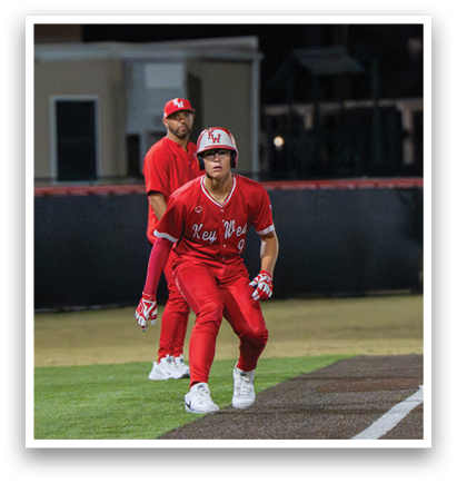 Two men in red uniforms are standing on a baseball field. One of them is holding a baseball bat, and the other is wearing a baseball glove. AI generated content
