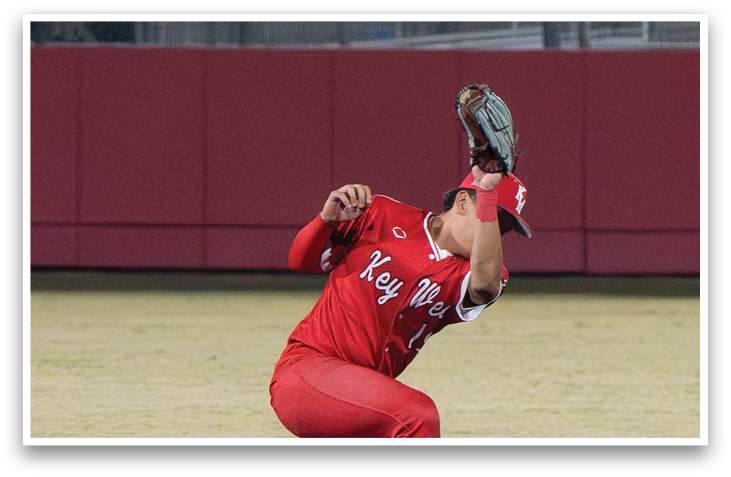 A baseball player in a red uniform is bending over and catching a ball with his glove. AI generated content