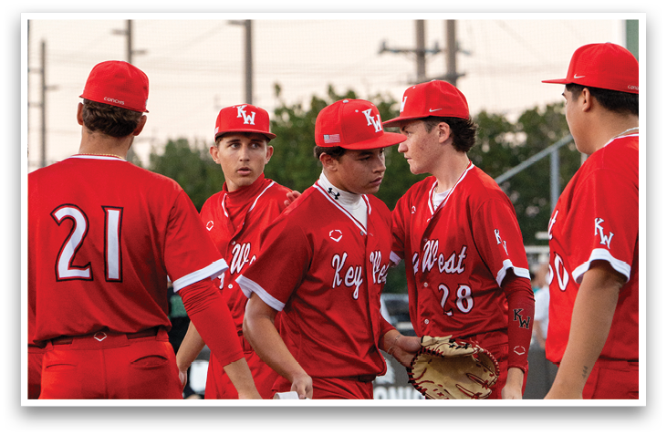 A group of baseball players wearing red uniforms and red hats are standing on a field. AI generated content