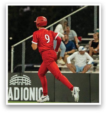 A baseball player wearing a red jersey with the number 9 on it is running on the field. AI generated content