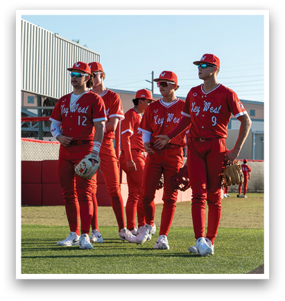 Four baseball players wearing red uniforms and red hats stand on a field. AI generated content