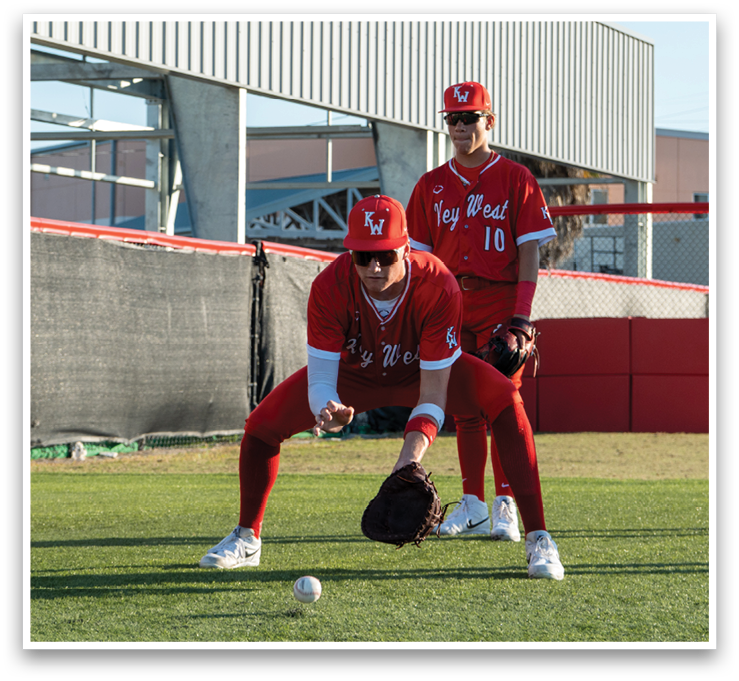 A baseball player in a red jersey is bending over to catch a ball. AI generated content