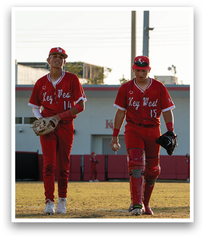Two baseball players wearing red uniforms and white hats are walking on a field. AI generated content