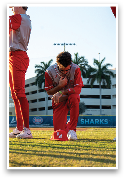 Three baseball players are standing on a field. One player is kneeling down and touching his hat. AI generated content