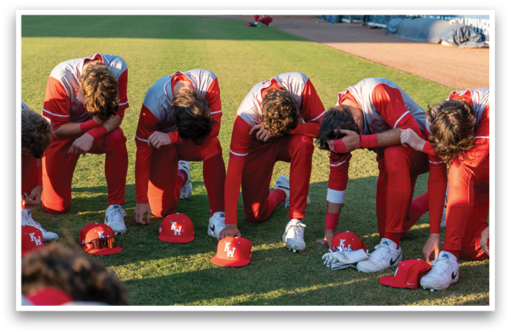 Baseball players wearing red uniforms and red hats, kneeling on the grass. AI generated content