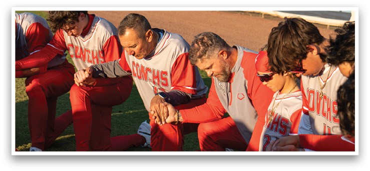 A group of baseball players kneeling in the dirt, praying before a game. AI generated content