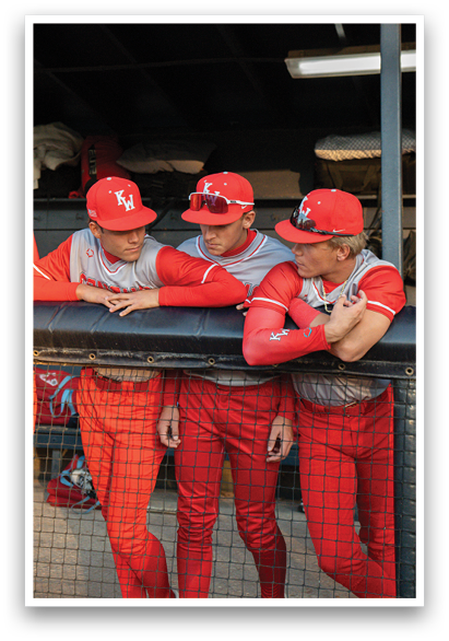 Three baseball players wearing red uniforms and red hats are leaning on a fence. AI generated content