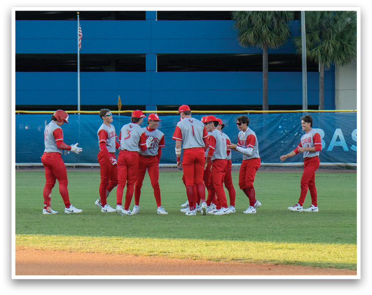 A group of baseball players wearing red uniforms are standing on a field. AI generated content