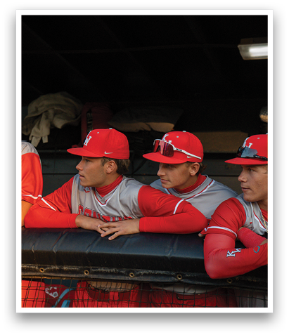 Three baseball players wearing red hats and jerseys are sitting on a bench. AI generated content