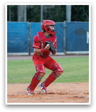 A baseball player in a red uniform is crouched down, holding a baseball glove. AI generated content