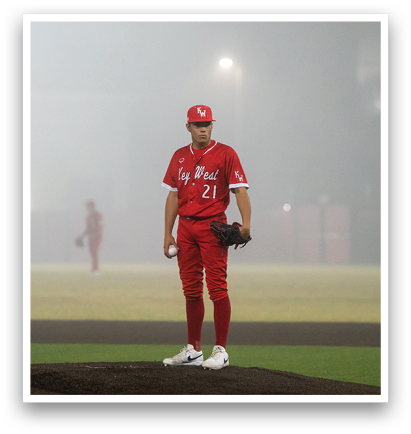 A baseball player in a red uniform stands on the pitcher's mound, holding a baseball in his hand. AI generated content