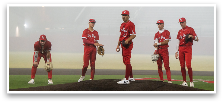 A group of baseball players are standing on a field, wearing red uniforms. They are holding baseball gloves and are positioned in various locations on the field. AI generated content
