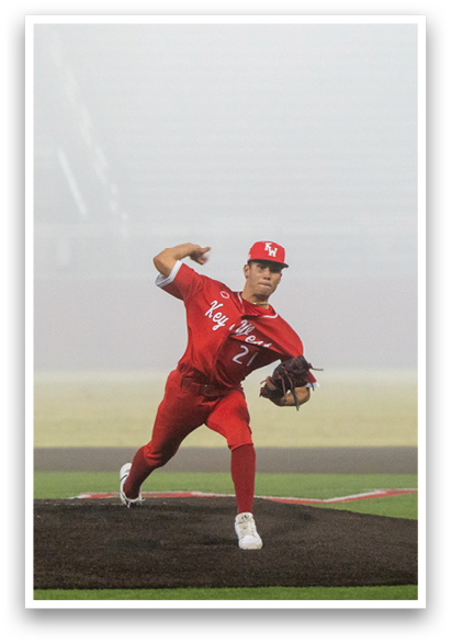 A baseball player in a red jersey is pitching a ball on a field. AI generated content