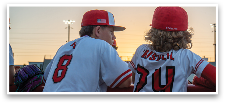 Two baseball players wearing red and white uniforms are sitting on a fence. AI generated content