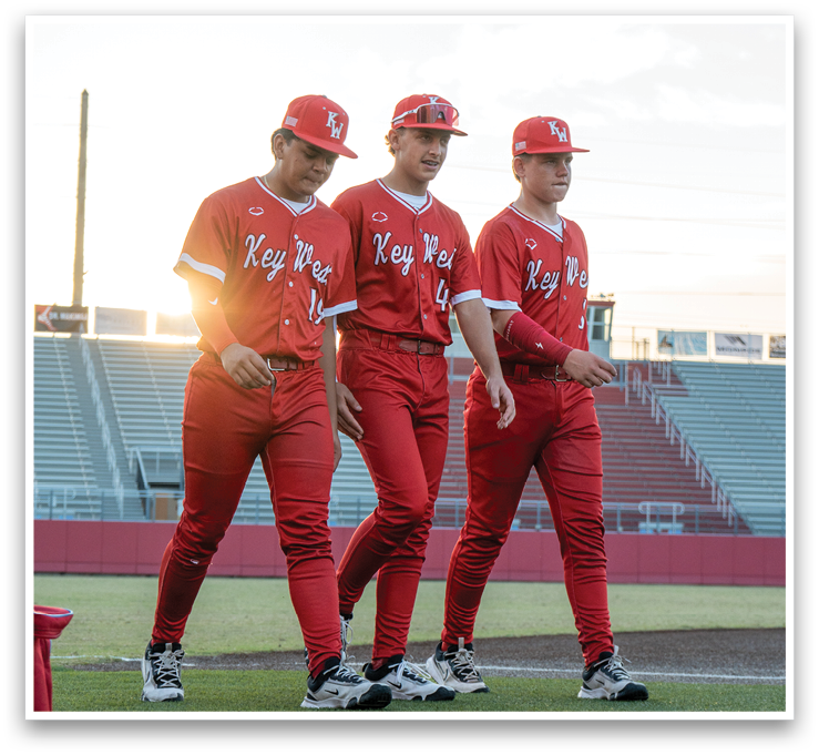 Three baseball players wearing red uniforms and red hats are walking on a field. AI generated content