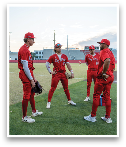 Four men in red uniforms are standing on a field, talking to each other. AI generated content